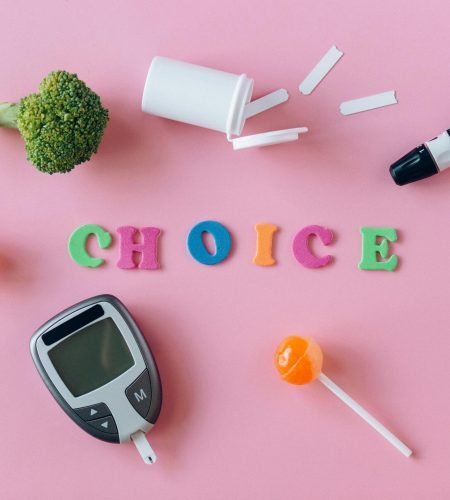 Artistic depiction of choosing between healthy food and sweets with glucose monitor on pink background.